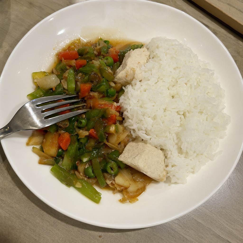 A plate with vegetables and protein eaten first, rice to the side