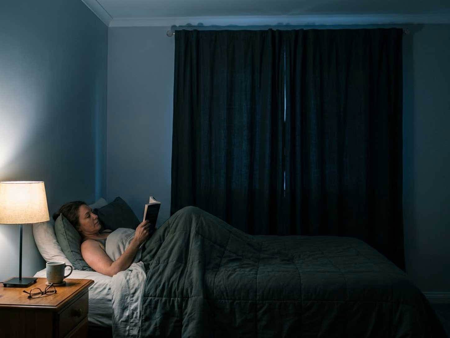 A dark, cool-toned bedroom with blackout curtains