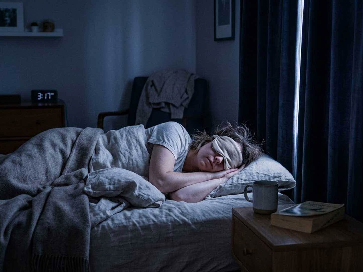 A person sleeping in a dark, cool bedroom